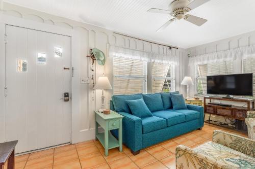 a living room with a blue couch and a tv at The Seashell Cottage in Anna Maria