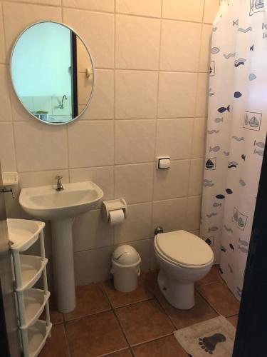 a bathroom with a sink and a toilet and a mirror at Pousada Farol do Marinheiro in Boicucanga