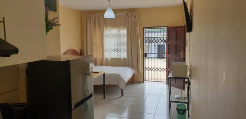 a room with a room with a bed and a refrigerator at Manzini, Park Vills Apartment, No 103 in Manzini