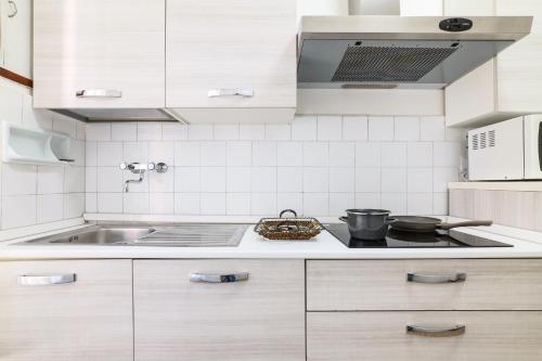 cocina con armarios blancos y fogones en Casa Primavera, en Bérgamo