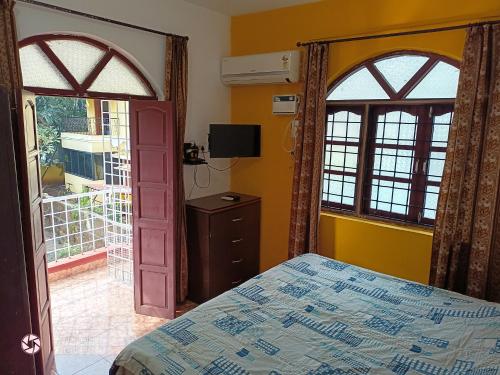 a bedroom with a bed and two large windows at AlexMarie Holiday Homes Apartments 5 min to Candolim Beach in Candolim