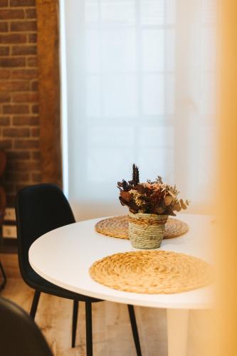 a table with two plates and a potted plant on it at SUITES BERRUETA , Plaza Mayor by Albany in León