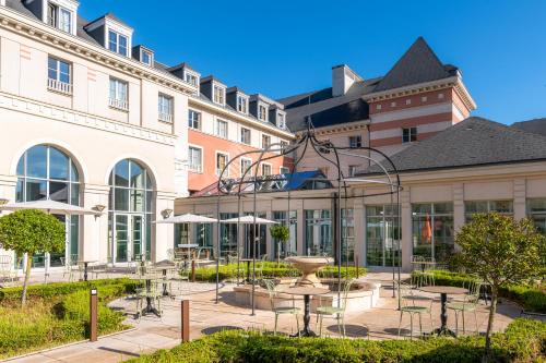 a courtyard with tables and a fountain in front of a building at Dream Castle Hotel Marne La Vallee in Magny-le-Hongre