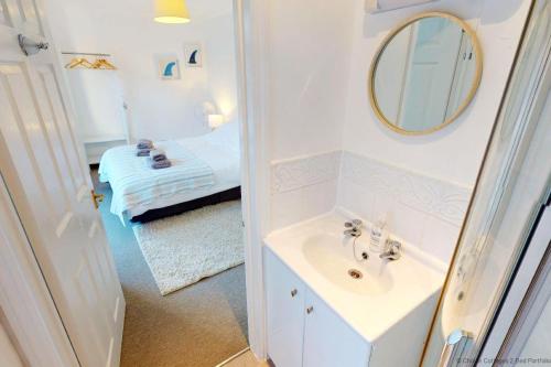 a bathroom with a sink and a mirror and a bed at ILFRACOMBE EDEN 2 Bedrooms in Ilfracombe