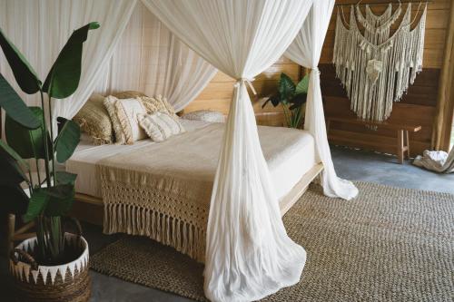 sypialnia z łóżkiem z baldachimem i białymi zasłonami w obiekcie AWERA RESORT w mieście Tua Pejat