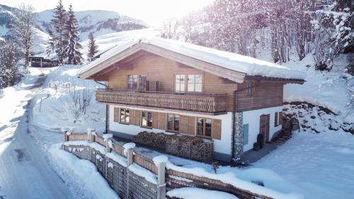 een blokhut in de sneeuw met zonneschijn bij Ski-in & Ski-out out Chalet Maria with amazing mountain view in Maria Alm am Steinernen Meer