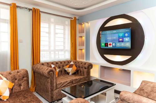 ein Wohnzimmer mit einem Sofa und einem TV an der Wand in der Unterkunft Springstone executive apartment Rm 15 in Langata Rongai