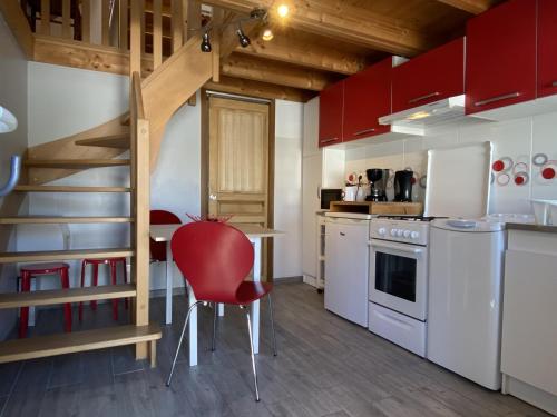 une cuisine avec des placards rouges et un fauteuil rouge dans l'établissement Charmante maison en pierre à Été, proche mer, plages, sentiers côtiers, idéale pour 2 personnes - FR-1-397-16, à Étel