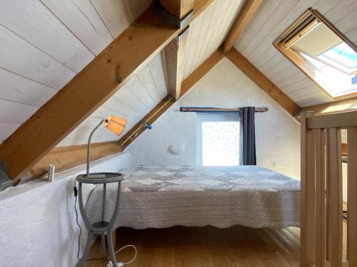- une petite chambre mansardée avec un lit et une fenêtre dans l'établissement Charmante maison en pierre à Été, proche mer, plages, sentiers côtiers, idéale pour 2 personnes - FR-1-397-16, à Étel