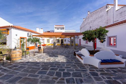 eine Terrasse mit Sofas und Tischen sowie ein Gebäude in der Unterkunft Luxury Palm Suites in Reguengos de Monsaraz