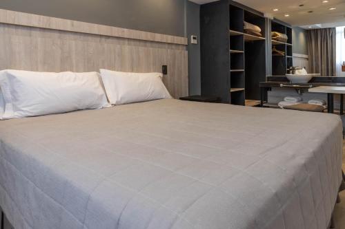 uma cama grande com almofadas brancas num quarto em HOTEL M em Mendoza