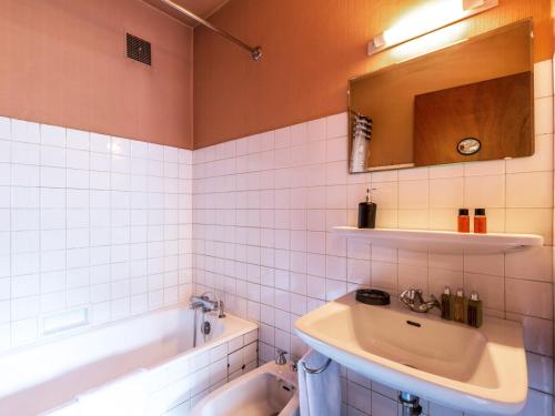 La salle de bains est pourvue de carrelage blanc, d'un lavabo et d'une baignoire. dans l'établissement Appartement 2 chambres centre village - Proche pistes, cheminée, animaux admis - FR-1-437-41, à La Clusaz