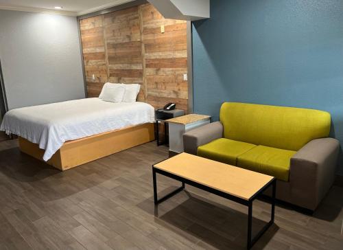 a bedroom with a bed and a couch and a chair at The Symphony Inn & Suites in Houston