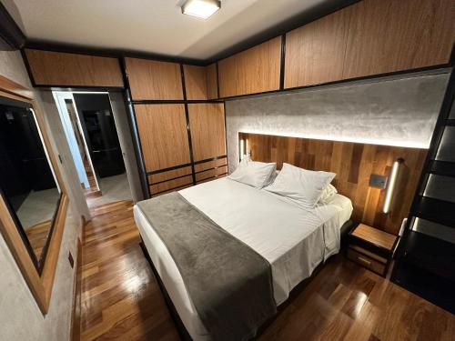 1 dormitorio con 1 cama en una habitación con paredes de madera en Flat 1092 Jardins, en São Paulo