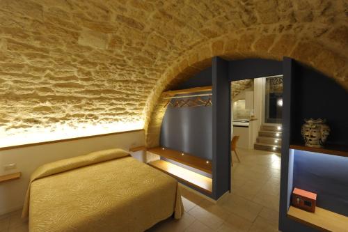 a bedroom with a bed and a stone wall at Pietrabianca Santa Maria Apartments in Manfredonia