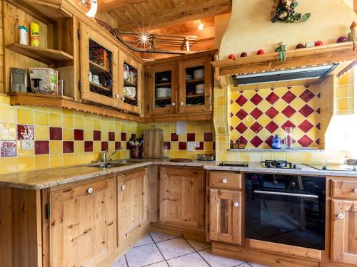 une cuisine avec des placards en bois et du carrelage jaune et rouge dans l'établissement Chalet 10 pers à La Clusaz - 5 ch - Calme - Cheminée - Animaux admis - Parking - FR-1-437-73, à La Clusaz