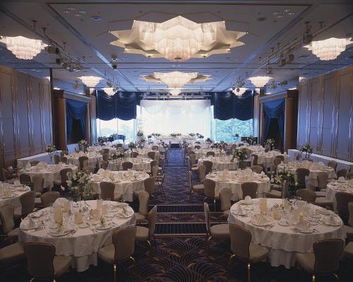 a banquet hall with white tables and chairs and a chandelier at Hotel New Grand in Yokohama