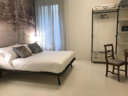 a bedroom with a bed and a chair and a window at "A casa di Giacomo" Luxury Rooms con aria condizionata in Bergamo