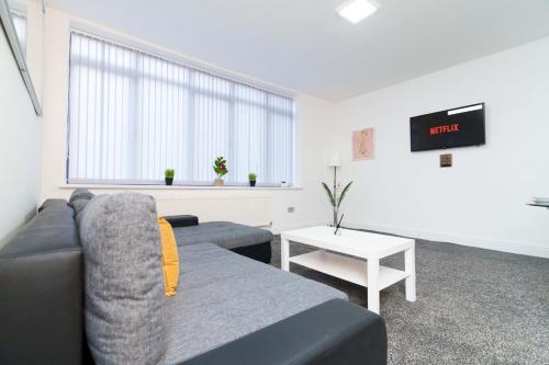 ein Wohnzimmer mit einem Sofa und einem Tisch in der Unterkunft Albion High Street Apartments in Leeds