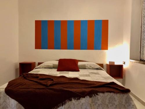 1 dormitorio con 1 cama con una pintura colorida en la pared en Casa del borghetto, en Intra