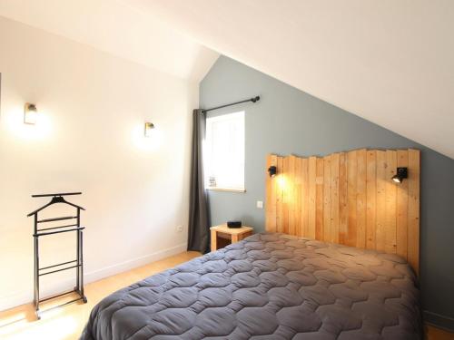 une chambre avec un grand lit avec une tête de lit en bois dans l'établissement Appartement T3 duplex proche centre 6 pers, équipé, cave privative - FR-1-608-44, à Le Mont-Dore