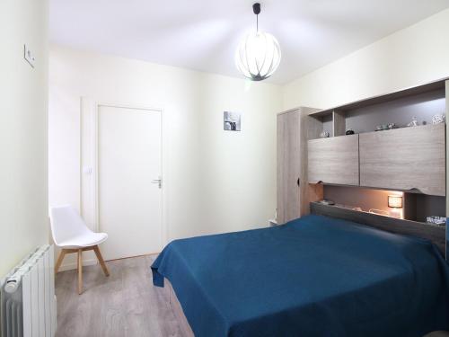 - une chambre avec un lit bleu et une chaise blanche dans l'établissement Bel appartement T2 rénové avec wifi au centre du Mont-Dore, proche des Thermes et pistes - FR-1-608-181, à Le Mont-Dore