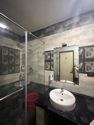 a bathroom with a sink and a shower and a mirror at PPH Living Athithi Inn Corporate Stay in Coimbatore