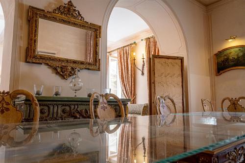 uma sala de jantar com uma mesa de vidro e um espelho em Dimora Villa Ricci em Pedaso
