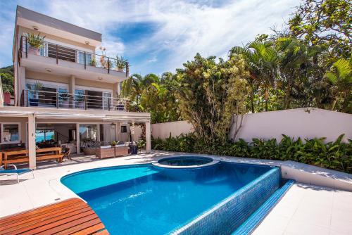a swimming pool in front of a house at Casa Margot - Casas de Luxo Pé na Areia in Juquei