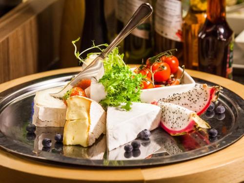 a plate of food with cheese and vegetables on a table at Qubus Hotel Gorzów Wielkopolski in Gorzów Wielkopolski