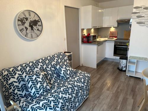 un salon avec un canapé et une horloge au mur dans l'établissement 2 Pieces acces Mer et Thalasso, à Cabourg