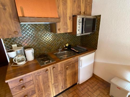 une petite cuisine avec un évier et un micro-ondes dans l'établissement Studio cosy au pied des pistes de Crêt Béni, sud avec balcon, parking inclus ! - FR-1-692-50, à La Chapelle-dʼAbondance