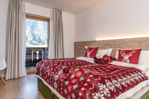 a bedroom with a bed with a red blanket and a window at Hotel Kronplatzer Hof in Rasun di Sopra