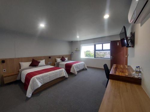 a hotel room with two beds and a television at Oaxaca Inn Reforma in Oaxaca City