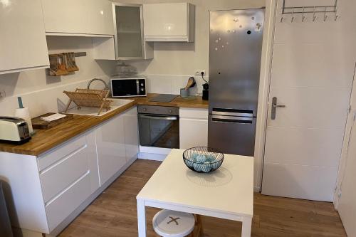 a kitchen with white cabinets and a stainless steel refrigerator at Cosy's Kerguelen - Longère jardin in Larmor-Plage