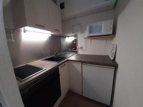 une petite cuisine avec un évier et un micro-ondes dans l'établissement Appartement rénové près de la plage, balcon SUD, quartier animé, parking gratuit - FR-1-239-114, à Seignosse