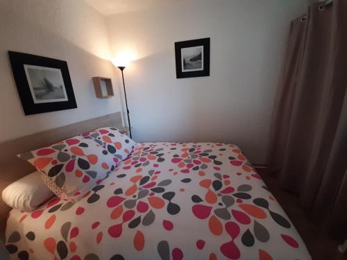 - une chambre avec un lit et une couette en fleurs dans l'établissement Appartement rénové près de la plage, balcon SUD, quartier animé, parking gratuit - FR-1-239-114, à Seignosse