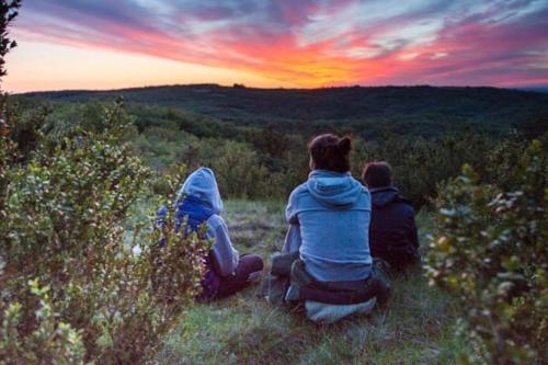 two people sitting on a hill watching the sunset at Les Trigones du Causse -Maison atypique avec Piscine Privée in Saint-Martin-Labouval