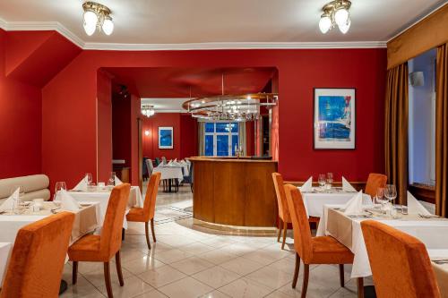 un restaurante con mesas y sillas blancas y paredes rojas en Spa & Wellness Hotel Silva en Mariánské Lázně