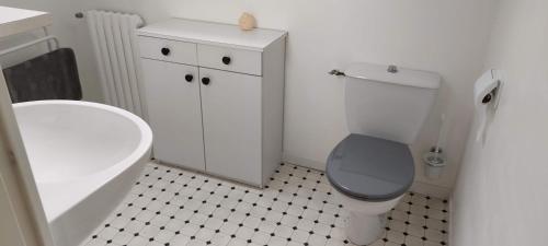 ein Badezimmer mit einem weißen WC und einem schwarz-weißen Boden in der Unterkunft Chambres au Village in Saint-Mʼhervé