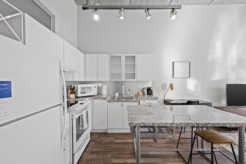 a kitchen with white cabinets and a table with chairs at Kasa South Side Pittsburgh in Pittsburgh