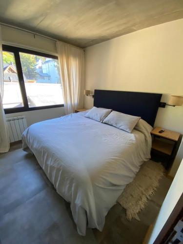 Un dormitorio con una gran cama blanca y una ventana en AIKEN 16 Terraza en San Martín de los Andes