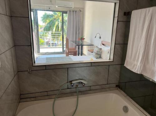 a bathroom with a bath tub with a window at Hôtel Grand Bay in Nosy Be