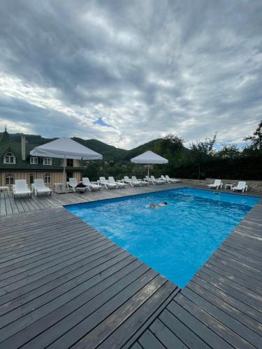 a person laying in a pool with chairs and umbrellas at Гірський узвіз in Vizhenka