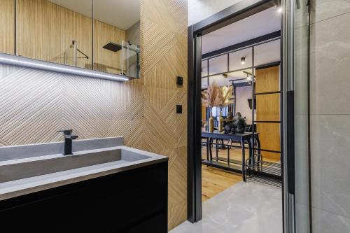 a bathroom with a sink and a mirror at APARTAMENT CHICAGO - stylowy apartament z KLIMATYZACJĄ o bardzo wysokim standardzie w centrum miasta, z prywatnym zadaszonym parkingiem - IZBY PODHALAŃSKIE in Nowy Targ