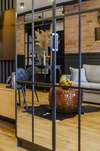 a room with a couch and a chair and a table at APARTAMENT CHICAGO - stylowy apartament z KLIMATYZACJĄ o bardzo wysokim standardzie w centrum miasta, z prywatnym zadaszonym parkingiem - IZBY PODHALAŃSKIE in Nowy Targ