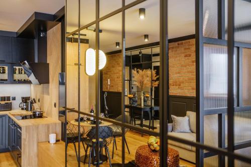 a kitchen with black cabinets and a brick wall at APARTAMENT CHICAGO - stylowy apartament z KLIMATYZACJĄ o bardzo wysokim standardzie w centrum miasta, z prywatnym zadaszonym parkingiem - IZBY PODHALAŃSKIE in Nowy Targ