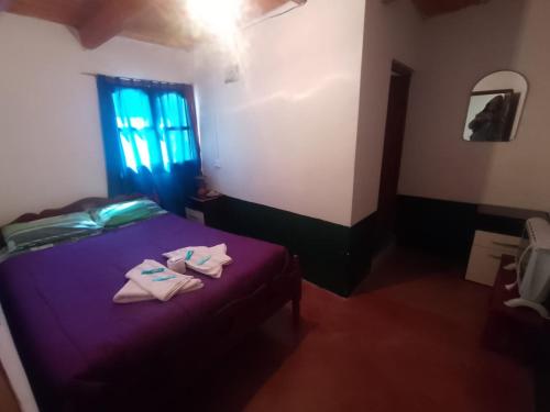a bedroom with a purple bed with towels on it at HOSTAL LUPITA in Iruya