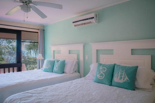a bedroom with two beds with blue and white pillows at Bahia Pez Vela Resort in Ocotal