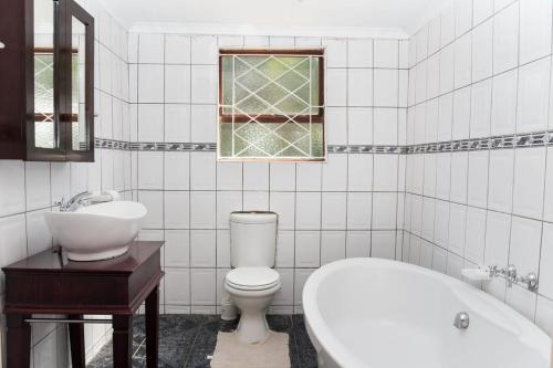 a bathroom with a toilet and a sink and a tub at Bisho Park guesthouse in King Williamʼs Town